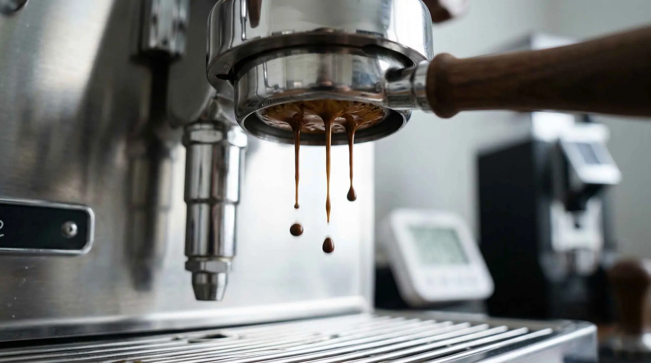 Macro shot of a bottomless portafilter with dark, viscous espresso dripping slowly, illustrating a choked shot and high puck resistance.